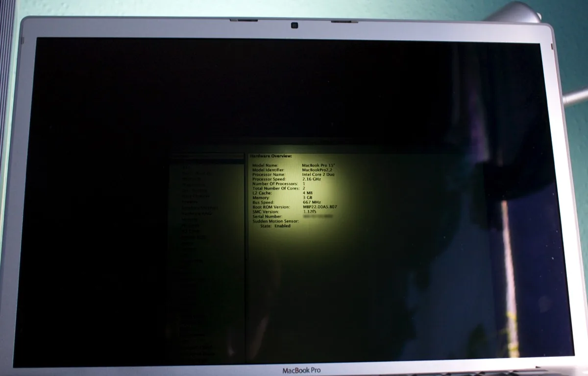 Schermo buio di un MacBook con l'immagine visibile solo puntandoci contro una luce