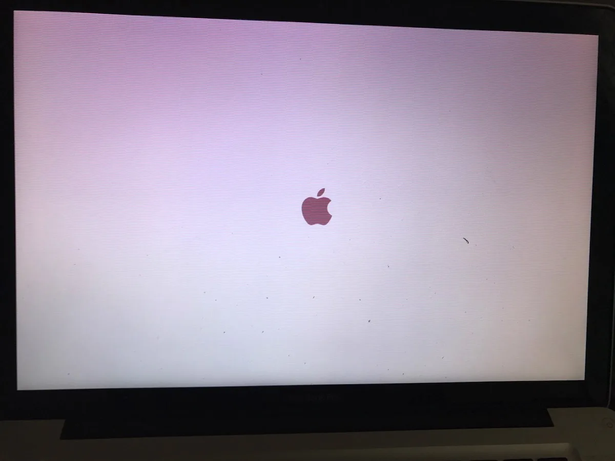 Schermo di un MacBook con dominante bianco-rosa e il logo Apple al centro
