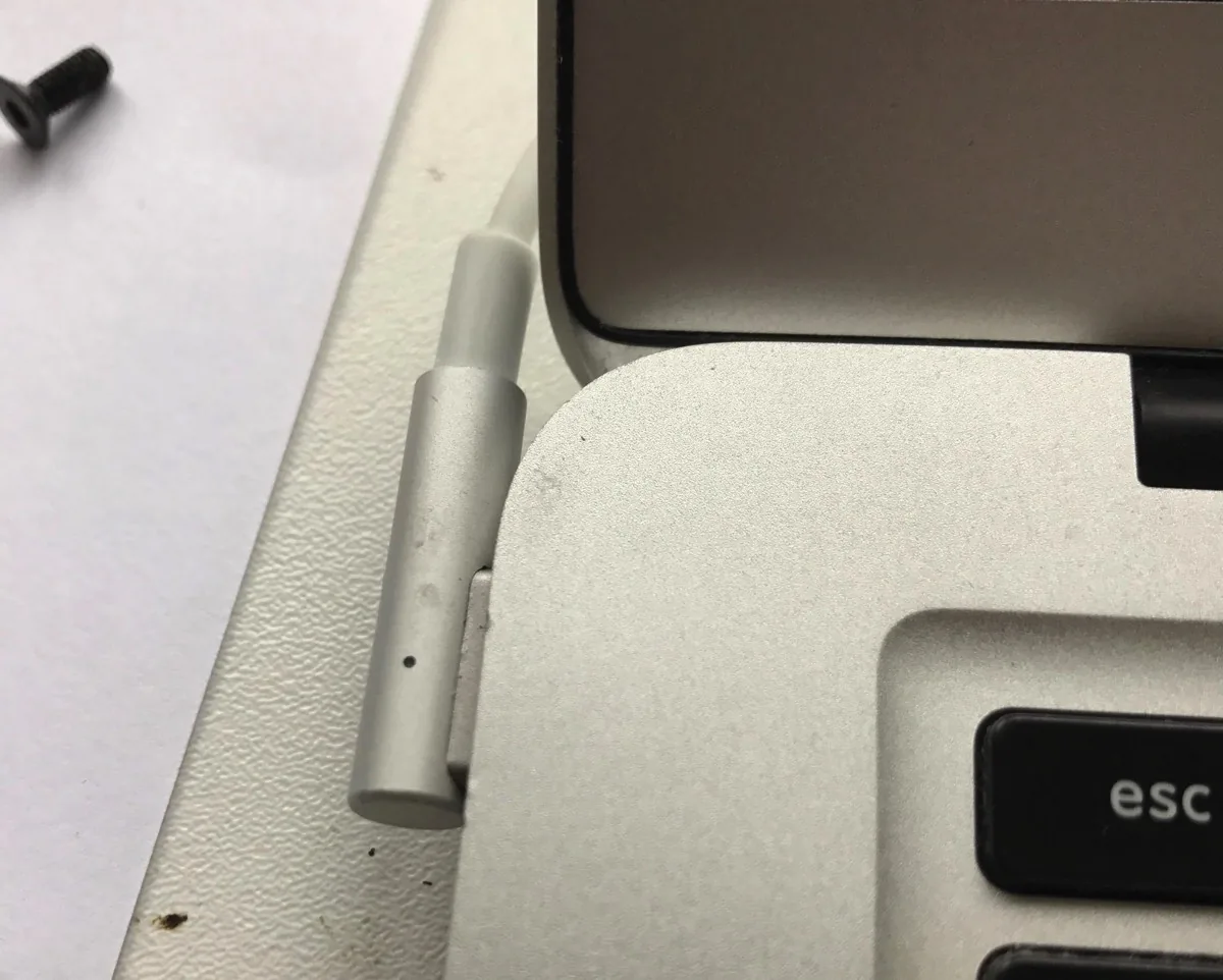 Alimentatore MagSafe accanto alla scocca di un MacBook che non carica la batteria